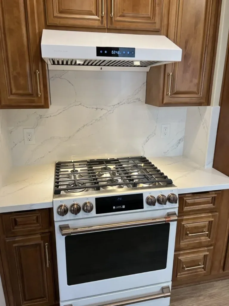 Gas range and hood set into a stone backsplash