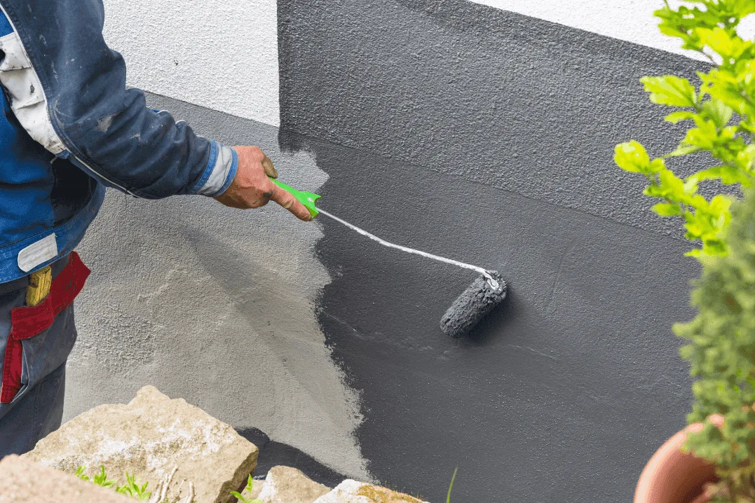 Painter rolling a fresh coat onto an exterior stucco wall